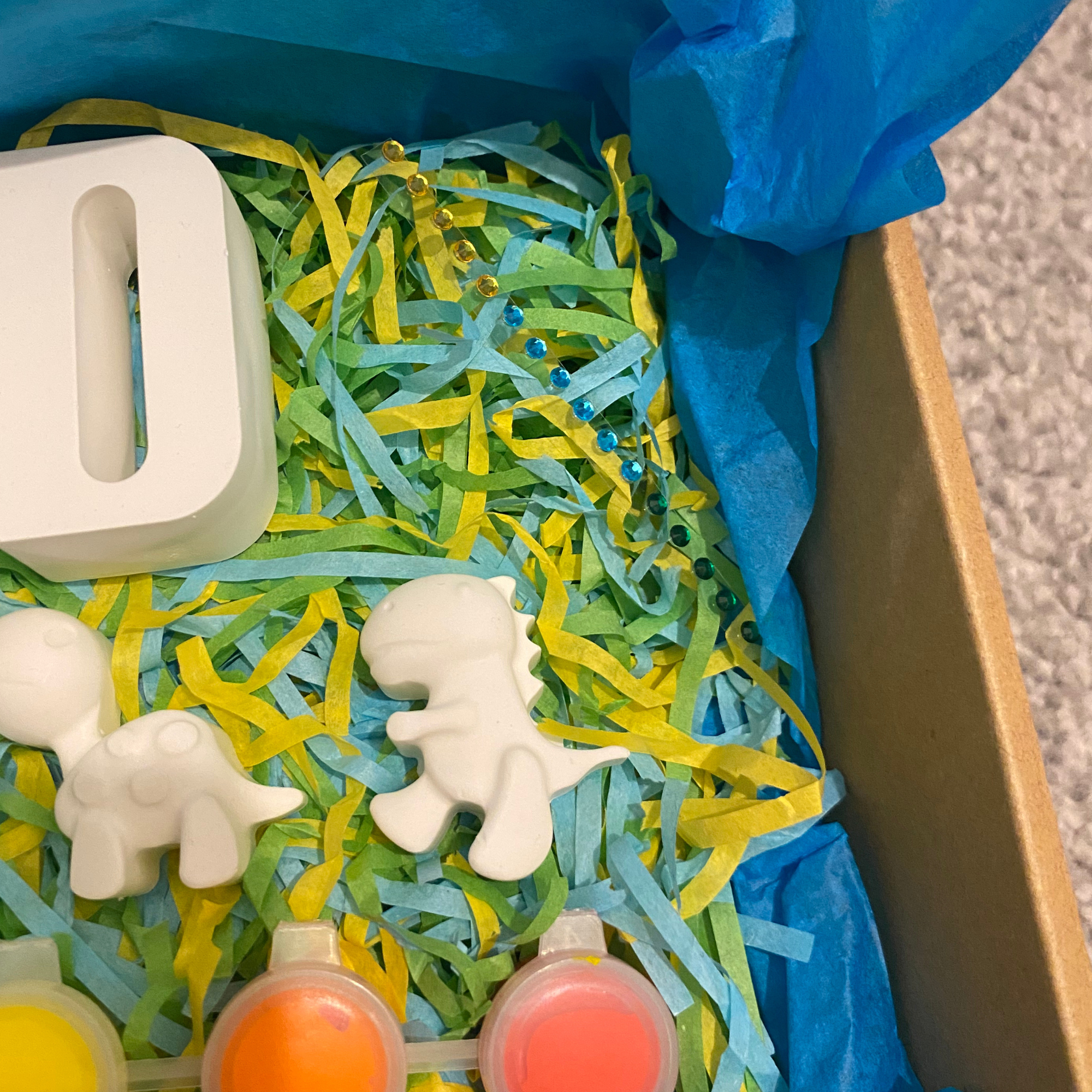 Dinosaur themed DIY paint kit set up with paints, brushes and moulds ready to decorate