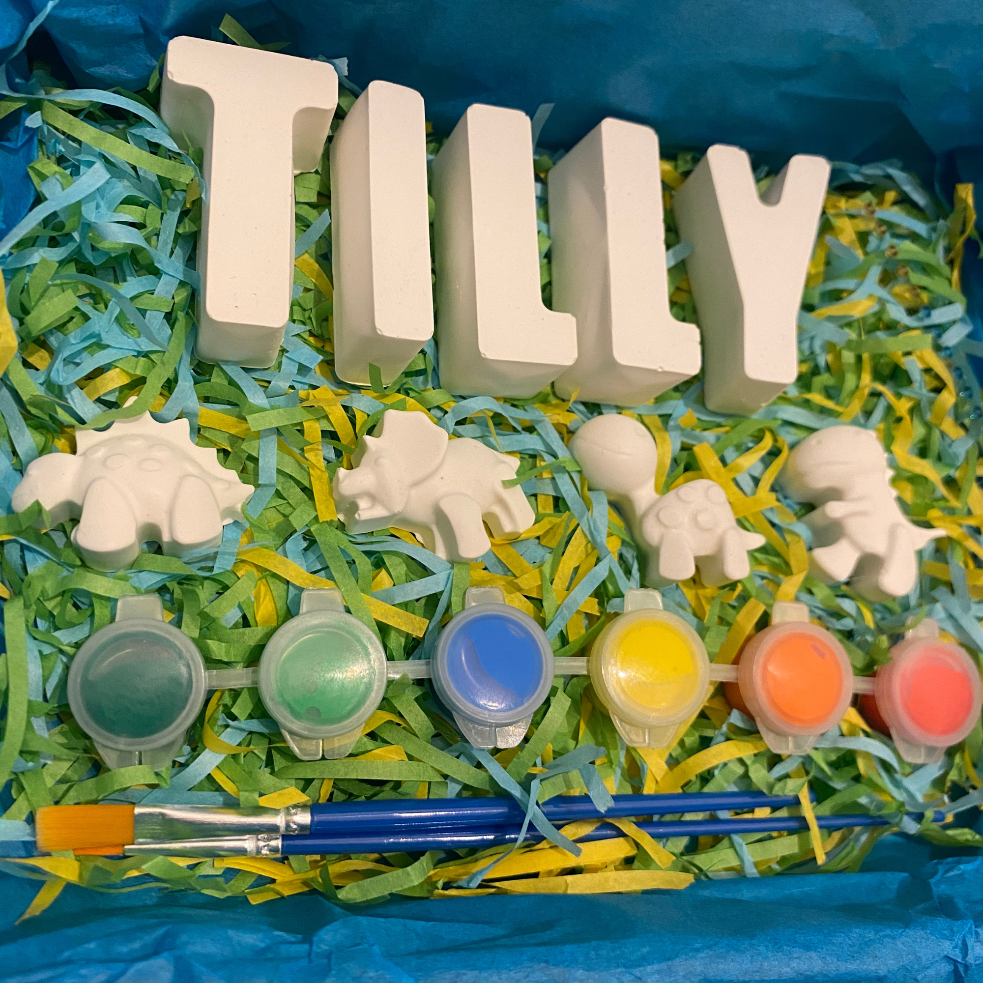 Dinosaur paint kit with dinosaur moulds, paints and brush displayed flat lay